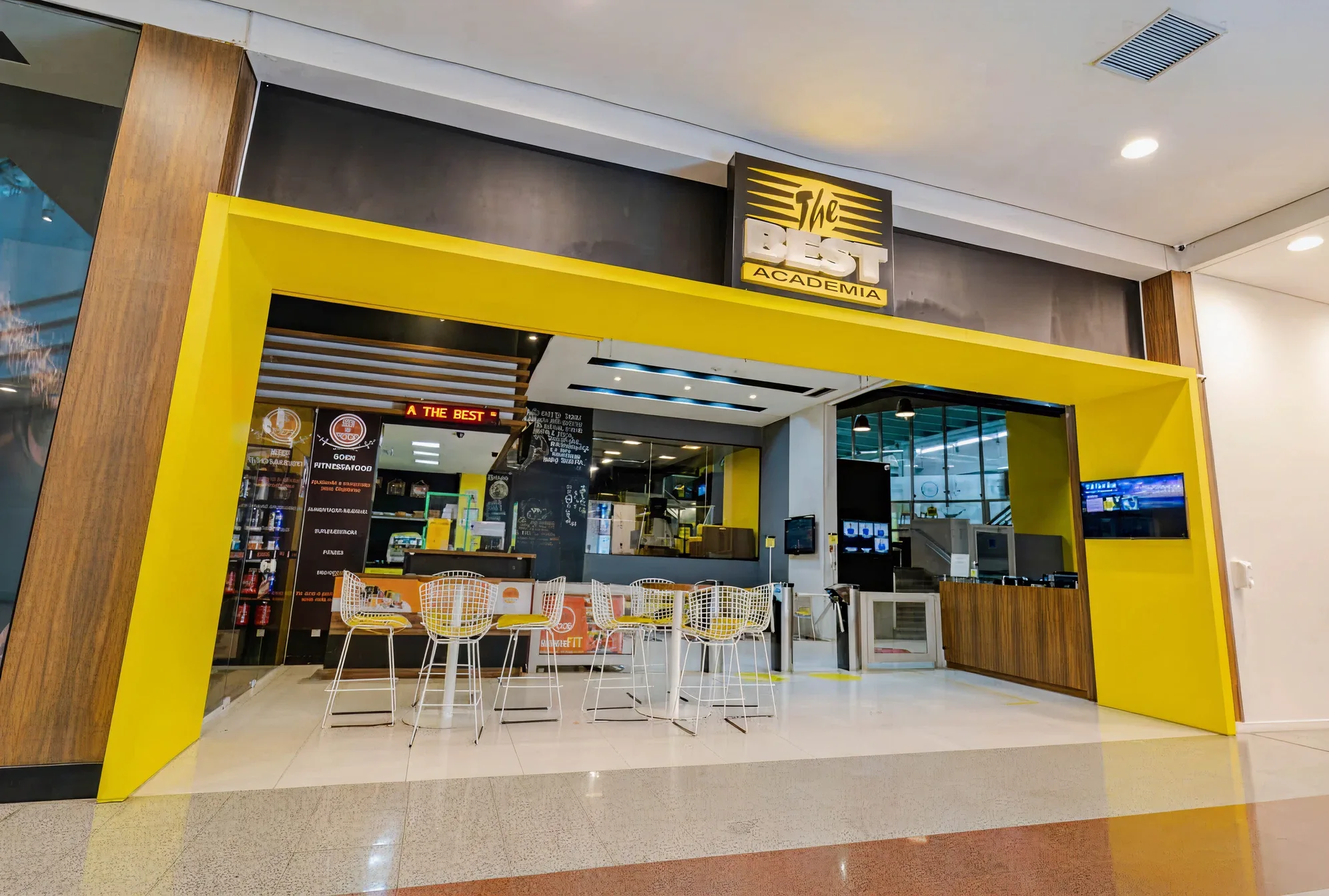 Entrada da The Best no piso do Shopping Mueller, com o pórtico amarelo e o letreiro da marca